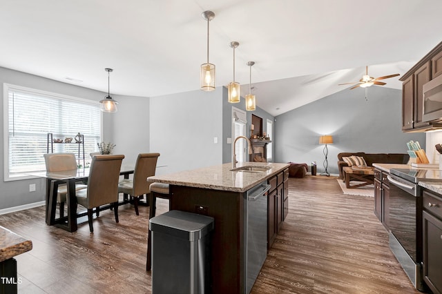 kitchen featuring pendant lighting, lofted ceiling, an island with sink, dark hardwood / wood-style flooring, and stainless steel appliances