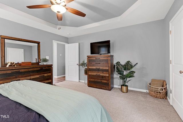 carpeted bedroom with a tray ceiling and ceiling fan