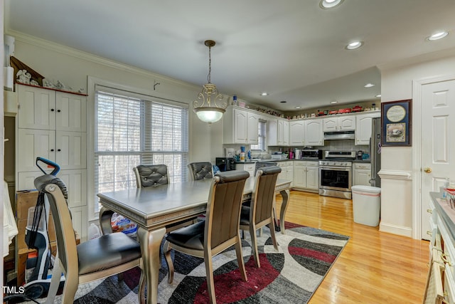 dining space with light hardwood / wood-style floors and ornamental molding