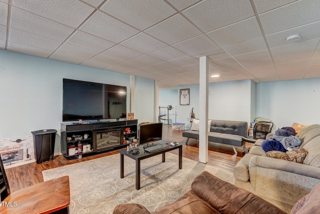 living room featuring wood-type flooring and a paneled ceiling