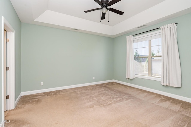 unfurnished room featuring ceiling fan, light colored carpet, and a tray ceiling