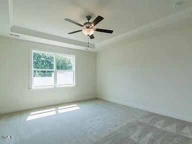 carpeted empty room featuring a tray ceiling and ceiling fan