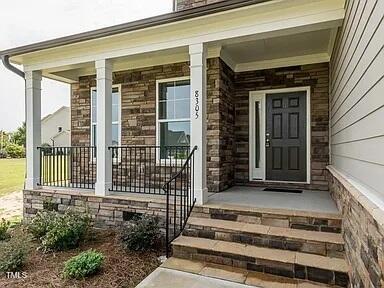 doorway to property with stone siding and a porch