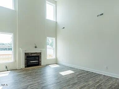 unfurnished living room featuring a wealth of natural light, a glass covered fireplace, and wood finished floors