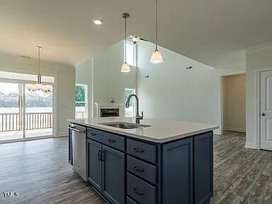 kitchen featuring dishwasher, decorative light fixtures, sink, and a kitchen island with sink