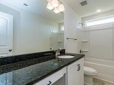 bathroom with toilet, visible vents, vanity, tile patterned floors, and washtub / shower combination