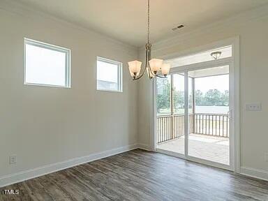 spare room featuring baseboards, dark wood finished floors, and a notable chandelier