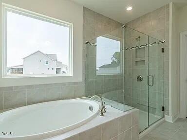 full bathroom featuring tile patterned flooring, a garden tub, and a shower stall