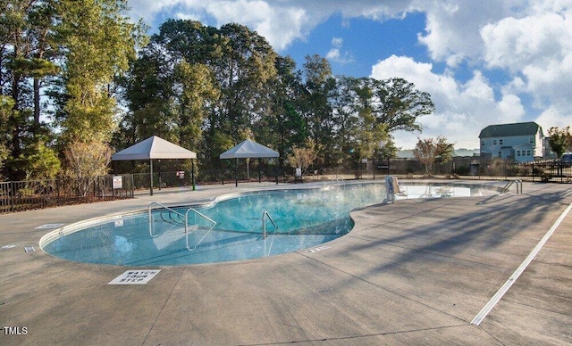 pool with a patio area and fence