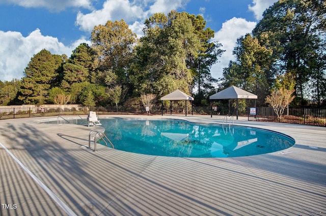 community pool with a patio area and fence