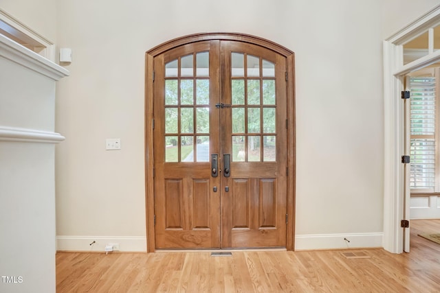 entrance foyer featuring hardwood / wood-style flooring, plenty of natural light, and french doors