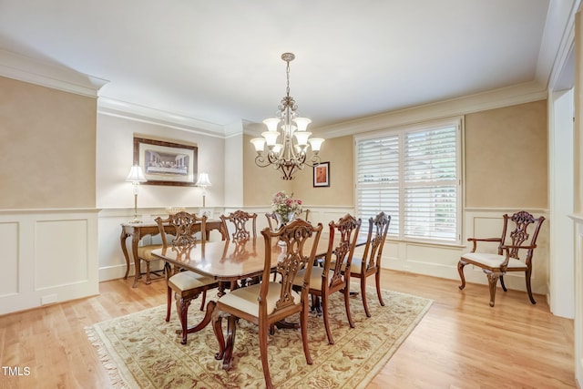 dining area with light hardwood / wood-style flooring, ornamental molding, and a notable chandelier