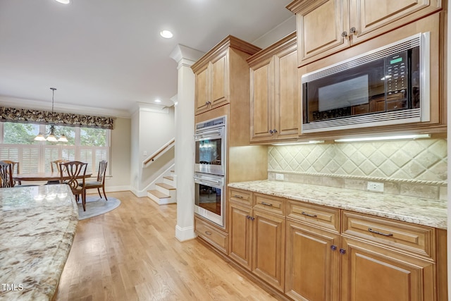 kitchen featuring built in microwave, stainless steel double oven, decorative light fixtures, backsplash, and light stone counters