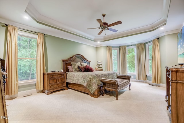 carpeted bedroom featuring ceiling fan, a tray ceiling, and ornamental molding