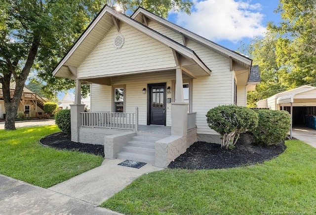 bungalow-style home with a carport, covered porch, and a front yard