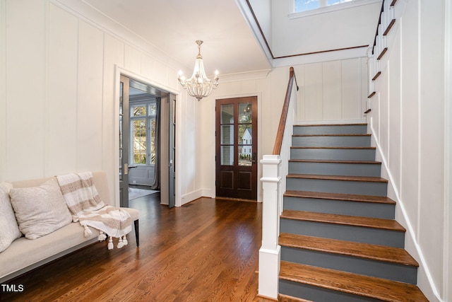 foyer entrance featuring an inviting chandelier, crown molding, and dark wood-type flooring