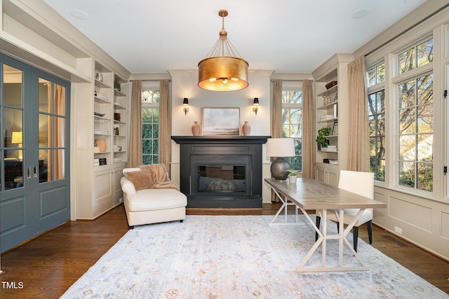 sitting room featuring a wealth of natural light, built in features, and dark hardwood / wood-style floors