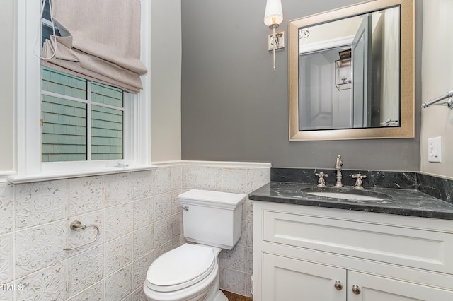 bathroom featuring vanity, tile walls, and toilet