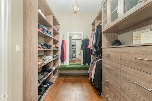 spacious closet featuring light hardwood / wood-style flooring and a notable chandelier