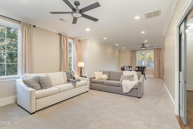 carpeted living room with crown molding and ceiling fan