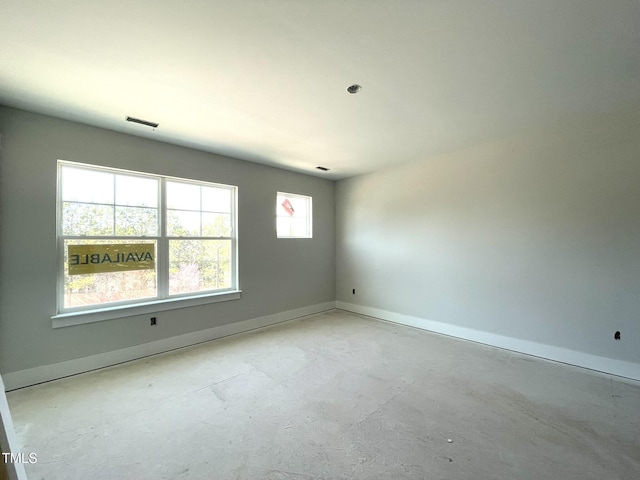 spare room with baseboards, unfinished concrete floors, and visible vents