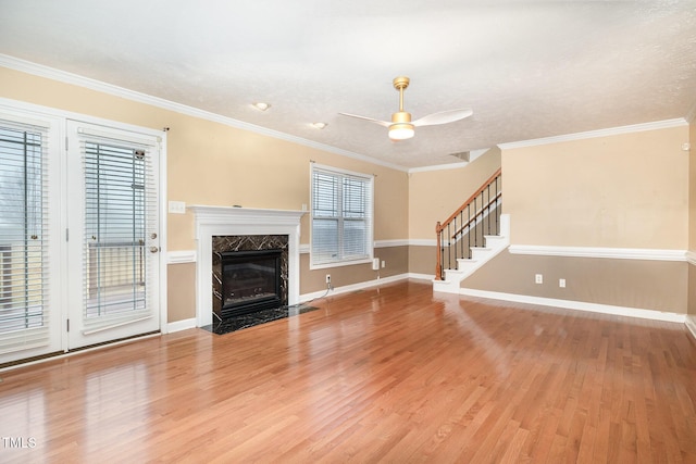 unfurnished living room with crown molding, hardwood / wood-style flooring, ceiling fan, a premium fireplace, and a textured ceiling