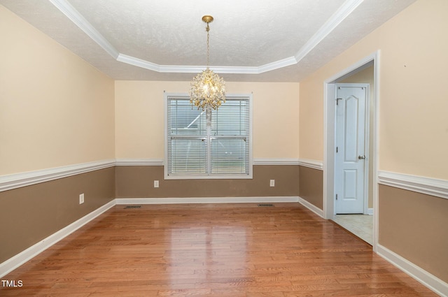 unfurnished dining area with hardwood / wood-style flooring, crown molding, and a tray ceiling