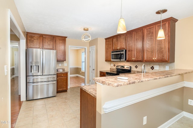 kitchen with kitchen peninsula, appliances with stainless steel finishes, light stone counters, and hanging light fixtures