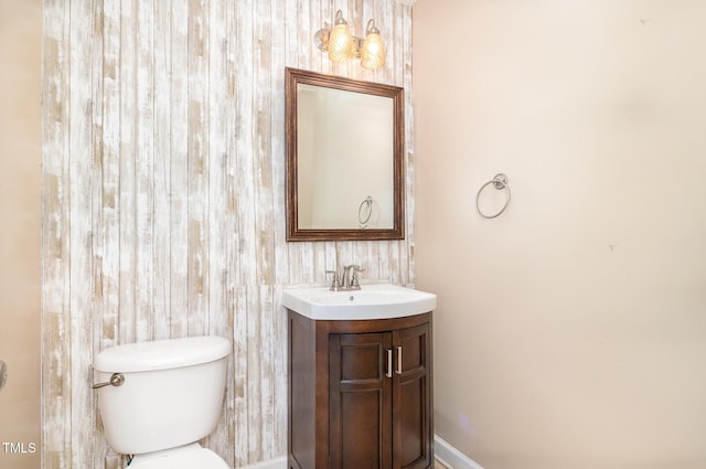 bathroom with vanity, toilet, and wooden walls