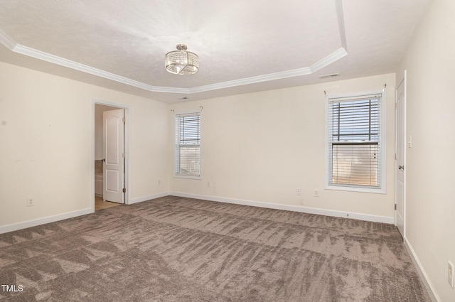 carpeted empty room with a textured ceiling, a healthy amount of sunlight, crown molding, and a tray ceiling