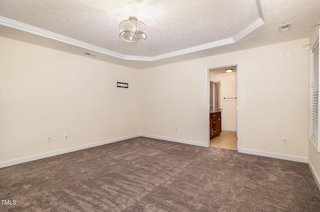 spare room with carpet, a textured ceiling, a tray ceiling, crown molding, and a notable chandelier