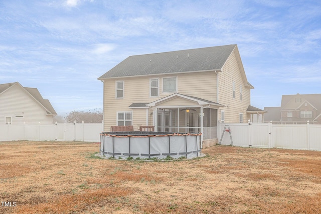 rear view of house featuring a lawn, a sunroom, and a covered pool