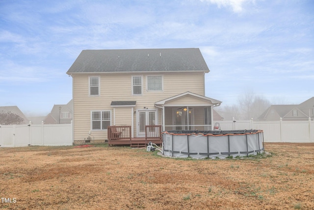 rear view of property featuring a sunroom, a swimming pool side deck, and a yard