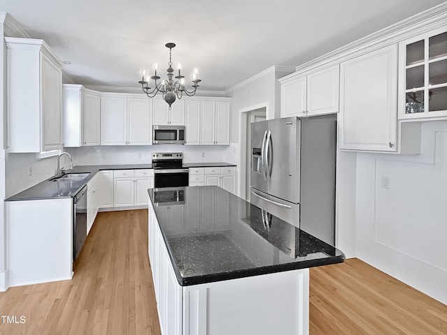 kitchen with white cabinetry, a center island, a notable chandelier, appliances with stainless steel finishes, and light wood-type flooring