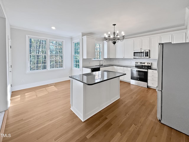 kitchen with white cabinetry, sink, hanging light fixtures, appliances with stainless steel finishes, and light wood-type flooring