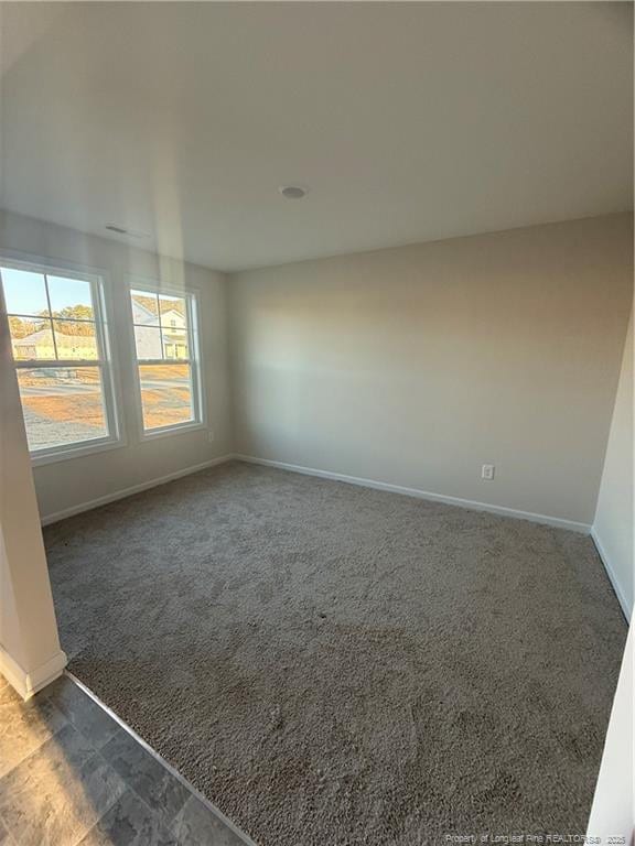 carpeted spare room featuring baseboards