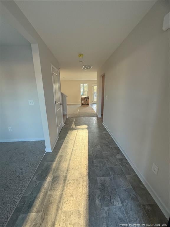 hall featuring baseboards and visible vents