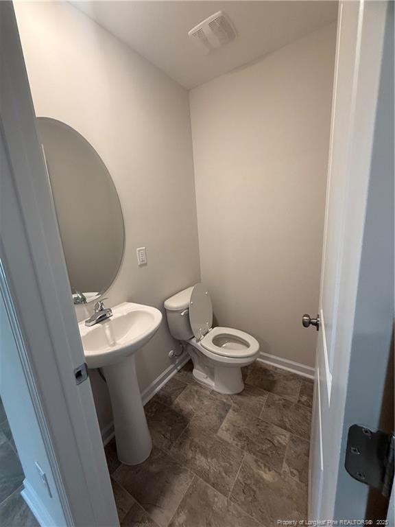 half bath with baseboards, visible vents, a sink, and toilet