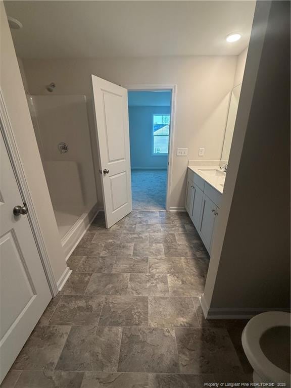 full bath with stone finish floor, baseboards, a shower stall, and vanity