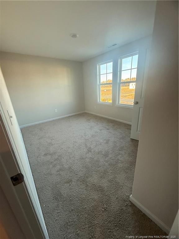 unfurnished room featuring carpet floors, visible vents, and baseboards