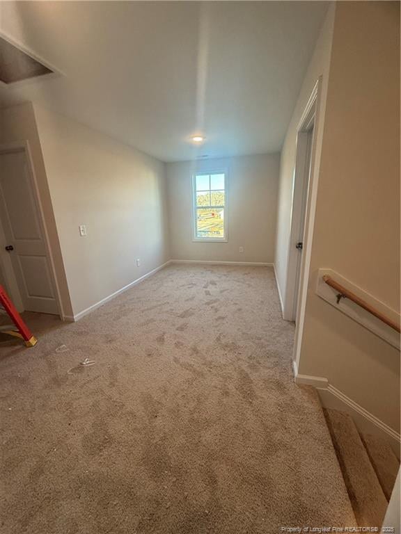 spare room featuring light carpet and baseboards