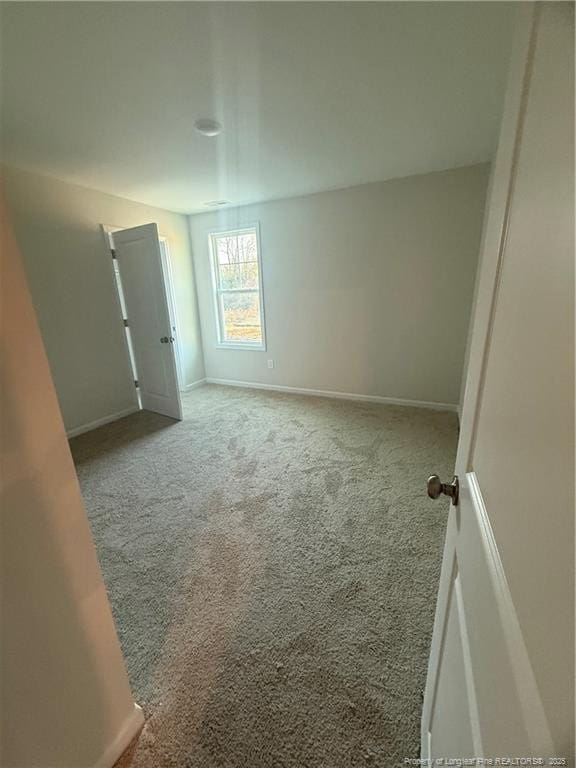 empty room featuring carpet and baseboards