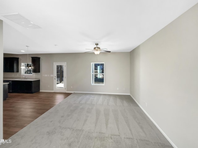 unfurnished living room with ceiling fan, wood-type flooring, and sink