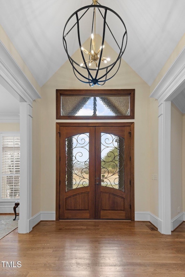 foyer with an inviting chandelier, light hardwood / wood-style floors, french doors, and lofted ceiling