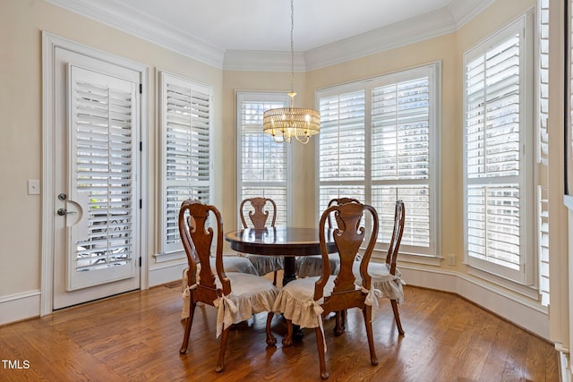 dining space featuring wood-type flooring, ornamental molding, and a chandelier