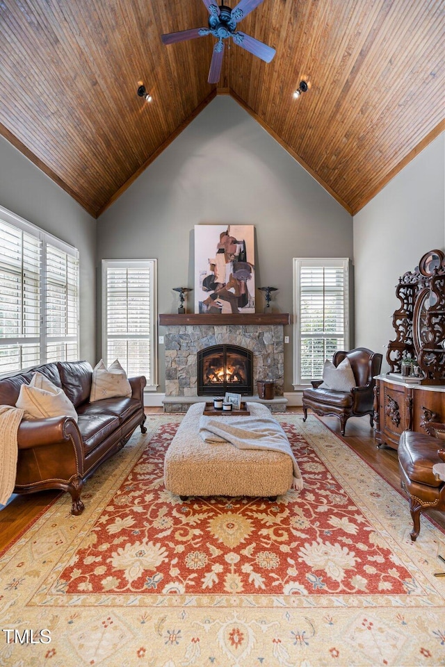 living room with ceiling fan, a stone fireplace, high vaulted ceiling, and wooden ceiling