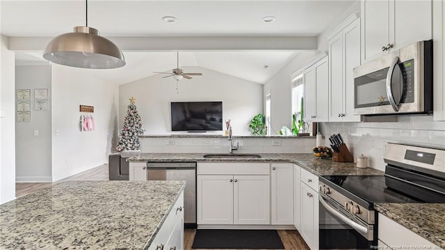 kitchen with white cabinets, appliances with stainless steel finishes, sink, backsplash, and vaulted ceiling