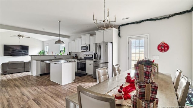 kitchen with appliances with stainless steel finishes, a center island, backsplash, hanging light fixtures, and kitchen peninsula