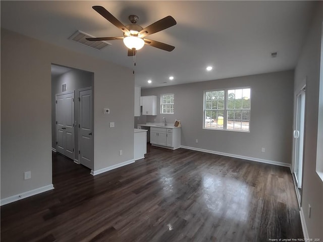 unfurnished living room with dark hardwood / wood-style floors, ceiling fan, and sink