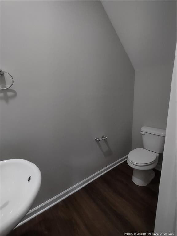 bathroom with hardwood / wood-style floors, toilet, and vaulted ceiling